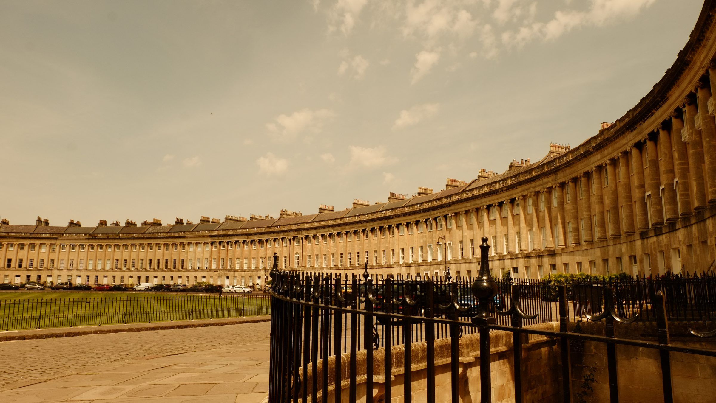 The long sweep of the Royal Crescent curving away over its lawn, iron railings in the foreground