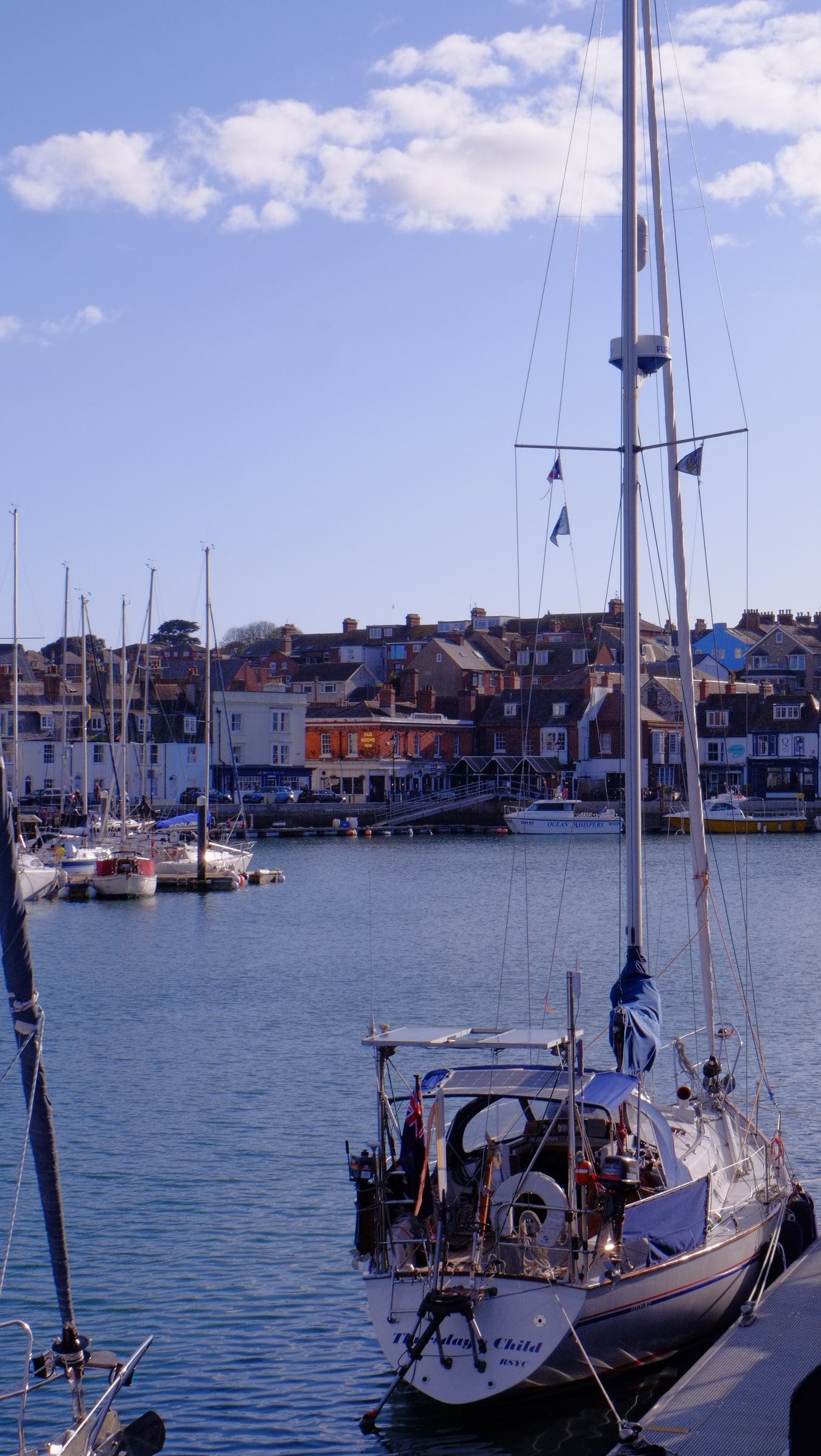 A single white yacht moored in the harbour, with colourful quayside houses across the water