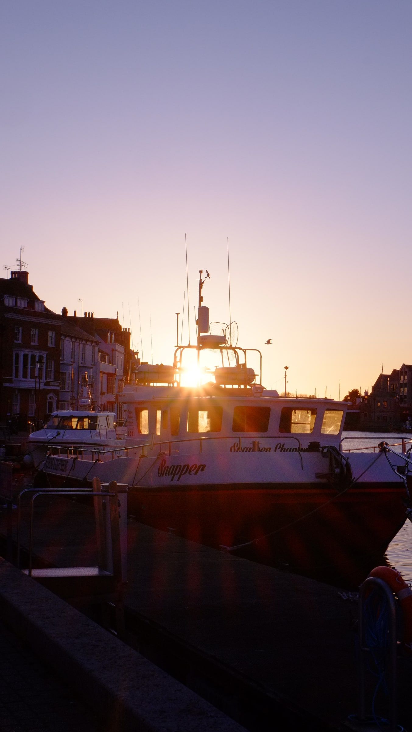 A moored boat silhouetted against a low evening sun over Weymouth harbour