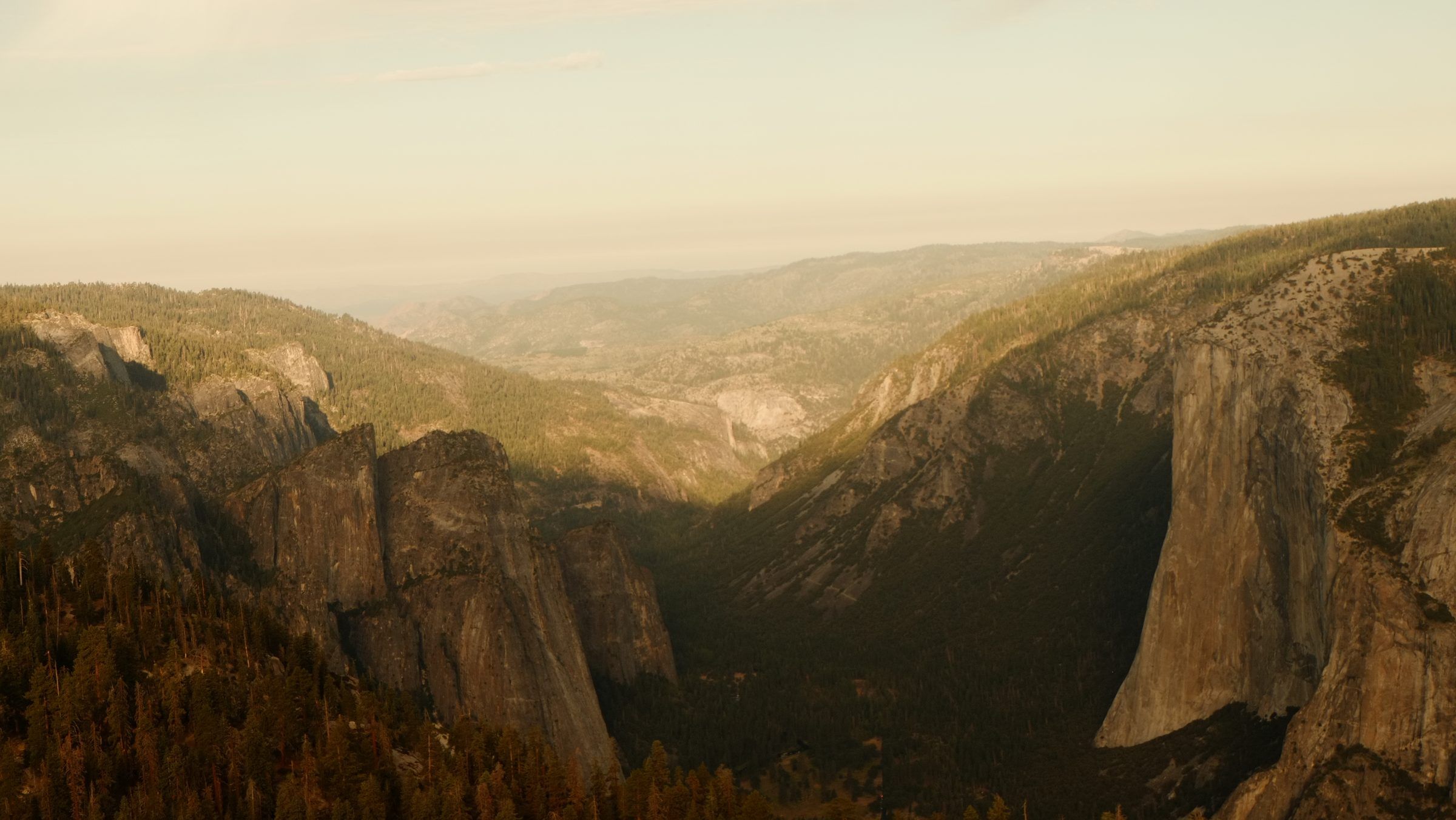 Yosemite Valley from above in golden evening light, El Capitan's sheer face on the right and granite spires on the left